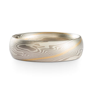 Mokume Gane ring or wedding band made by arn krebs, this ring is 6mm wide and has a low dome profile, it's made in our twist pattern and ash palette. The ash palette is palladium and sterling silver, and this ring also has an added yellow gold stratum that runs through the center of the pattern, twisting diagonally around the ring