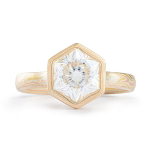 Mokume gane engagement ring  arn krebs, thin band with a large white stone, hexagon cut, at the center. The stone is surrounded by a handmade bezel in mokume as well, all yellow and red gold and silver