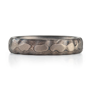 mokume guri bori metal ring that has higher points of flat metal with lines of metal running all around. topographical looking earth or land mass but made from precious metaL