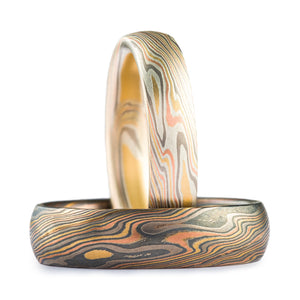 Light and dark pair of bands, both are made in a mokume gane twist pattern. The lighter one has an etched finish and the darker has an oxidized finish