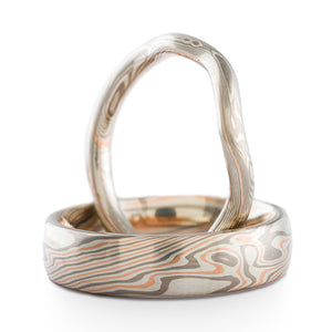 set of mokume gane wedding rings, one contoured to fit with an engagement ring