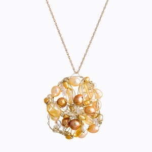 Pendant hanging on a silver chain, made by Susan Freda, champagne colored pearls of varying shades interwoven with champagne translucent beads, held together with twisted wire