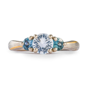 momkume gane engagement ring with three prong set stones, white center stone, side stones are blue