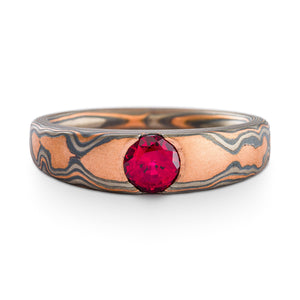 Mokume Gane ring or wedding ring by arn krebs with a cathedral style setting with a ruby, woodgrain pattern and embers palette, the embers palette is red gold palladium and silver, the ring is predominantly red gold