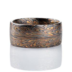 Wide mens ring mokume gane patterned to resemble the fibers of a feather, made with red and yellow gold, palladium, and oxidized silver (black) in thin layers.