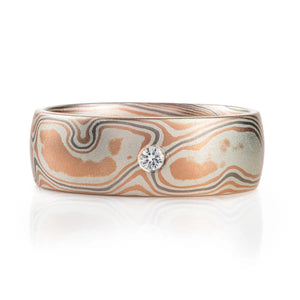 mokume gane band with red gold and silver, and one added palladium layer, ring also has a flush set moissanite in the center