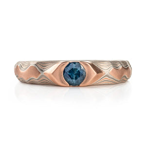 elegant wedding or engagement style ring in mokume gane guri bori pattern with a blue sapphire set into the center