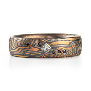 black and white diamonds flush set into a mokume gane band, red and yellow gold palladium and oxidized silver