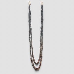 Long necklace made of thin oxidized chains that gradient towards copper at the bottom. The necklace is made of several strands, with tiny quartz stones sprinkled along it.