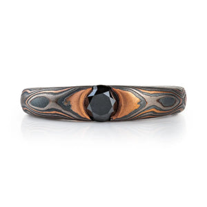 dark and moody feeling mokume gane ring, with solitaire black diamond in cathedral style setting, metals in the ring are red gold, palladium and oxidized silver