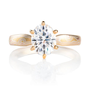 elegant six prong style engagement ring with an oval shaped diamond, band is woodgrain patterned and made in 18kt gold