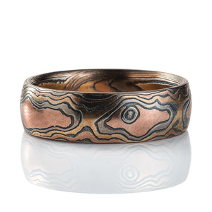 Warm toned mokume gane ring patterned to resemble wood, made with red gold, yellow gold and oxidized silver.