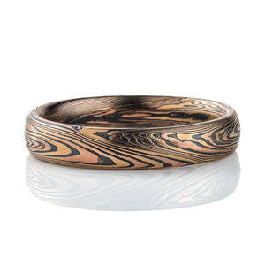 Intricately patterned mokume gane band with a twisting linear pattern, made with red and yellow gold and oxidized silver.