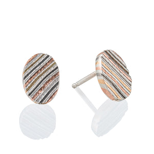 Mokume gane circular earrings patterned in a linear style, made with layers of red gold, yellow gold, palladium and silver.