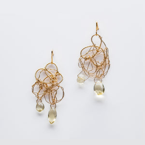 Spun wire earrings made with loops of yellow gold, each with two citrine crystals (light green) hanging from the bottom.