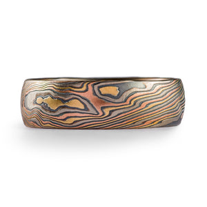 Mokume gane ring, made of alternating layers of red gold yellow gold and palladium with silver in between. Pattern resembles organic natural textures and travels in a twisting motion around the ring