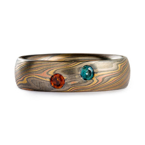 Mokume gane ring made by Arn Krebs, Firestorm palette and twist pattern. Low dome profile, and two 3mm stones flush set in, the stones are blue and orange. The ring itself is 6mm wide