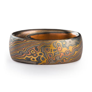 Mokume Gane ring made by arn krebs in a twist and droplet combination pattern. The ring is made of layers of red gold yellow gold and palladium with oxidized silver in between each. The ring is 7mm wide and has a low dome profile