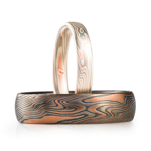 mokume gane band set, both in metal combination of red gold palladium and silver, larger ring is wider and has oxidized silver, while the smaller ring has a satin finish