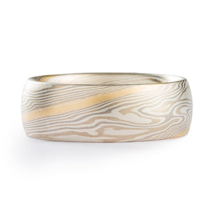 This beautiful 7mm Mokume Gane ring is shown in the Twist pattern and Smoke Palette, with a low dome profile, and a Satin finish with a medium etch. The Smoke palette features a three metal combination of 14k White Gold, Palladium, and Sterling Silver. This ring also features an added yellow gold stratum layer.