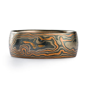 Mokume gane band or wedding ring made by arn krebs, this ring is made in our woodgrain pattern and embers palette. Our embers metal palette is made up of red gold, palladium and sterling silver, and the red gold is the dominant color. The ring is 8.5mm wide and has a low dome profile.