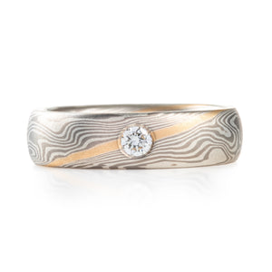 classic feeling mokume gane wedding ring with a flush set diamond and stratum layer accent