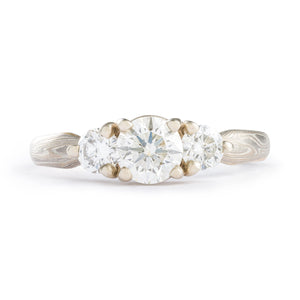 This gently tapered 3mm-2mm tapered Mokume Gane ring is shown in the Twist pattern and the Smoke metal combination. It also features three prong set diamonds, a low-dome profile, and an etched finish. The Smoke palette features 14k White Gold, Palladium and Sterling Silver. This ring also has a beautiful added yellow gold stratum.