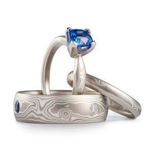 three piece mokume gane wedding set, engagement ring with blue sapphire and matching silvery colored bands with white and blue stones