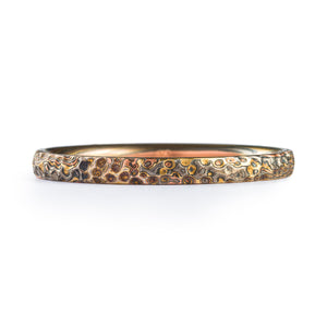 Mokume Gane patterned ring, very thin, made of layers of palladium red gold and yellow gold alternating with oxidized silver, and whole ring has carving made to resemble hammered metal