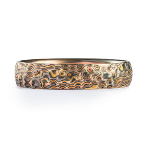 This beautiful and nature inspired Mokume Gane ring is shown in our Twist pattern and our Firestorm metal combination. The ring has a low-dome profile and an etched and oxidized finish. The Firestorm palette features 14kt yellow gold, 14kt red gold, palladium and sterling silver. This ring also has detailed surface carving done to create a hammered look!