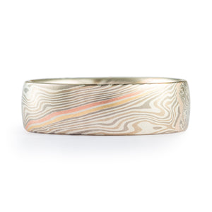 This unique and fun Mokume Gane ring is shown in the Twist pattern and Smoke Palette, with a low dome profile and satin finish. This design has two beautiful stratum layers added in, one red gold and one gold, side by side with a layer of silver in between, creating a pop of color in the more neutral overall palette.