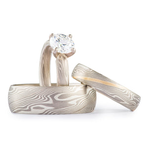 3 part ring set for engagement and/or wedding, all matching in twist pattern and silver colors. One ring has a prong set diamond, one has a yellow gold stratum layer. 