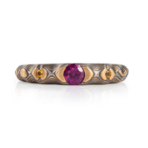 pink purple sapphire with cognac diamonds set in a mokume band of yellow gold, silver and palladium. the stones are set in yellow gold islands 