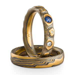 set of mokume gane rings, arn krebs guri bori pattern and twist pattern, upright ring has assorted blue and white flush set stones
