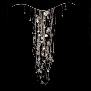 Metal silver wire chain tapestry with glass beads and white porcelain hanging on a curved steel bar